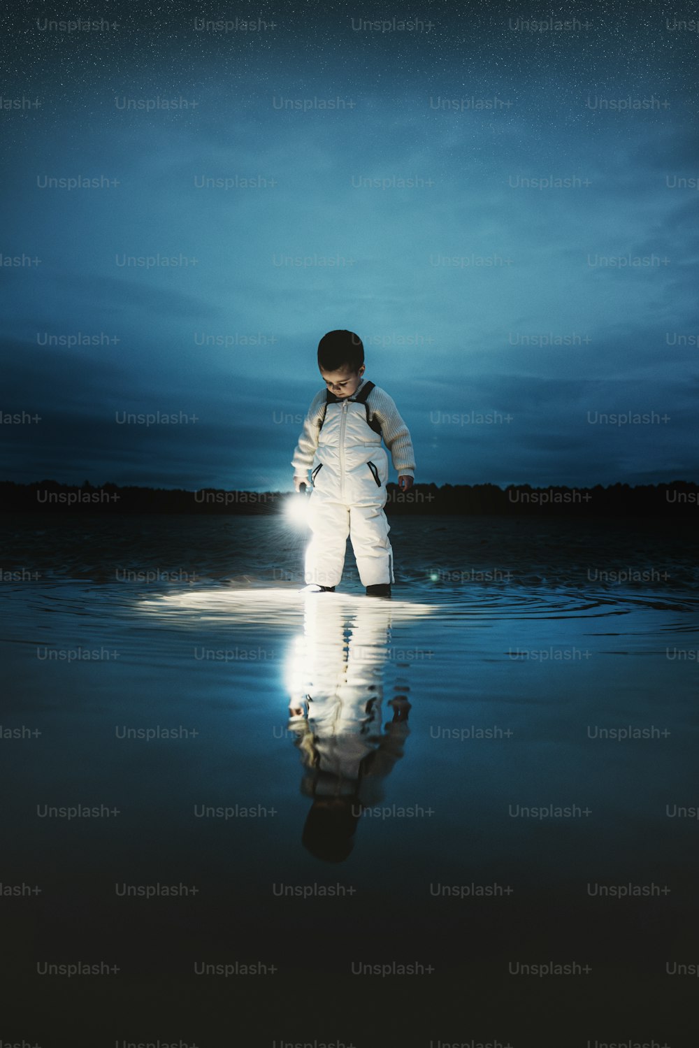un giovane ragazzo in piedi nell'acqua di notte
