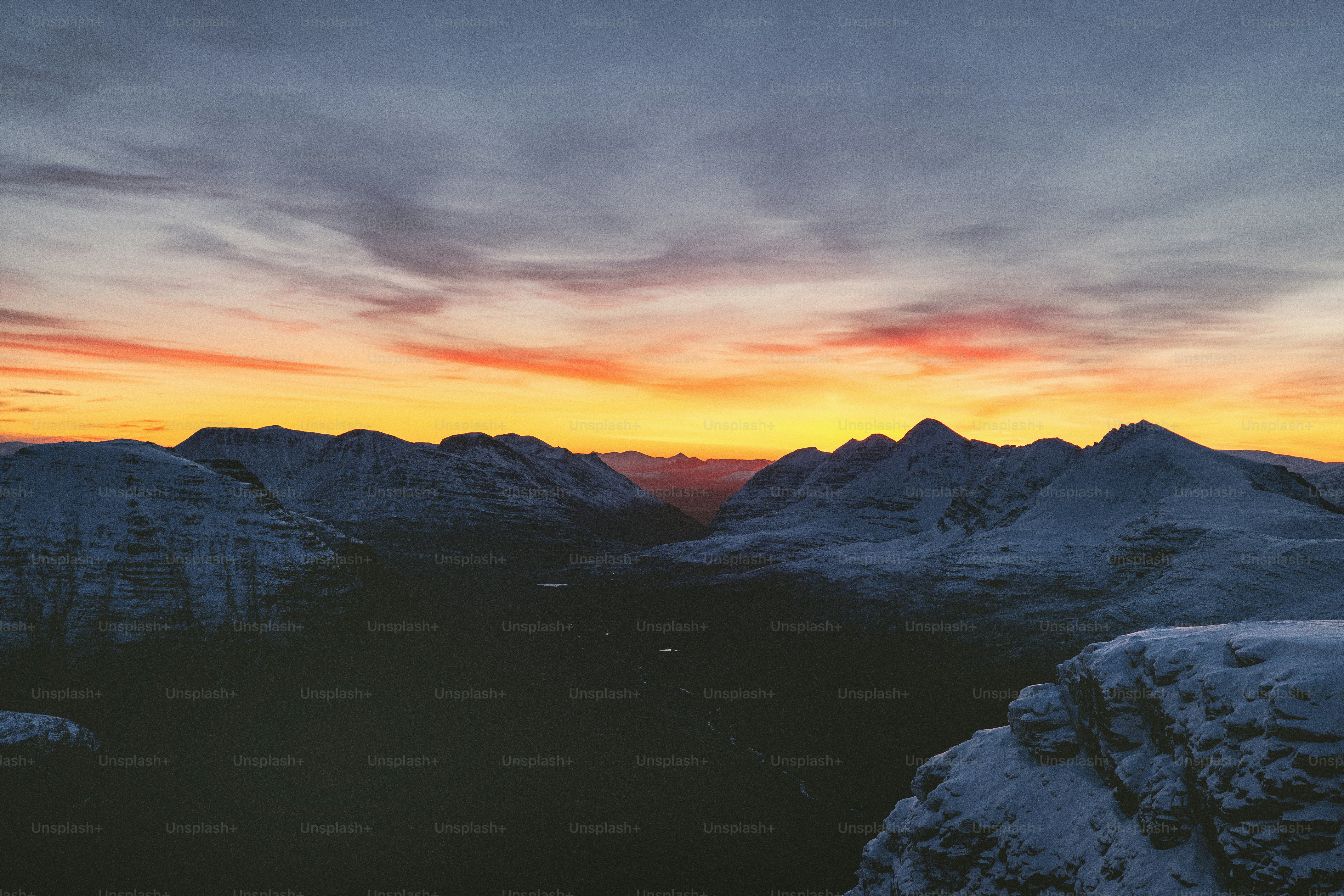 una veduta di una catena montuosa con un tramonto sullo sfondo