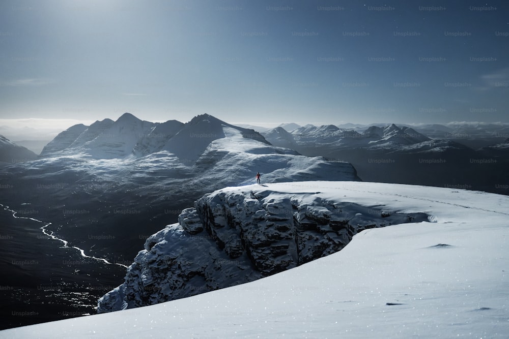 una persona de pie en la cima de una montaña cubierta de nieve