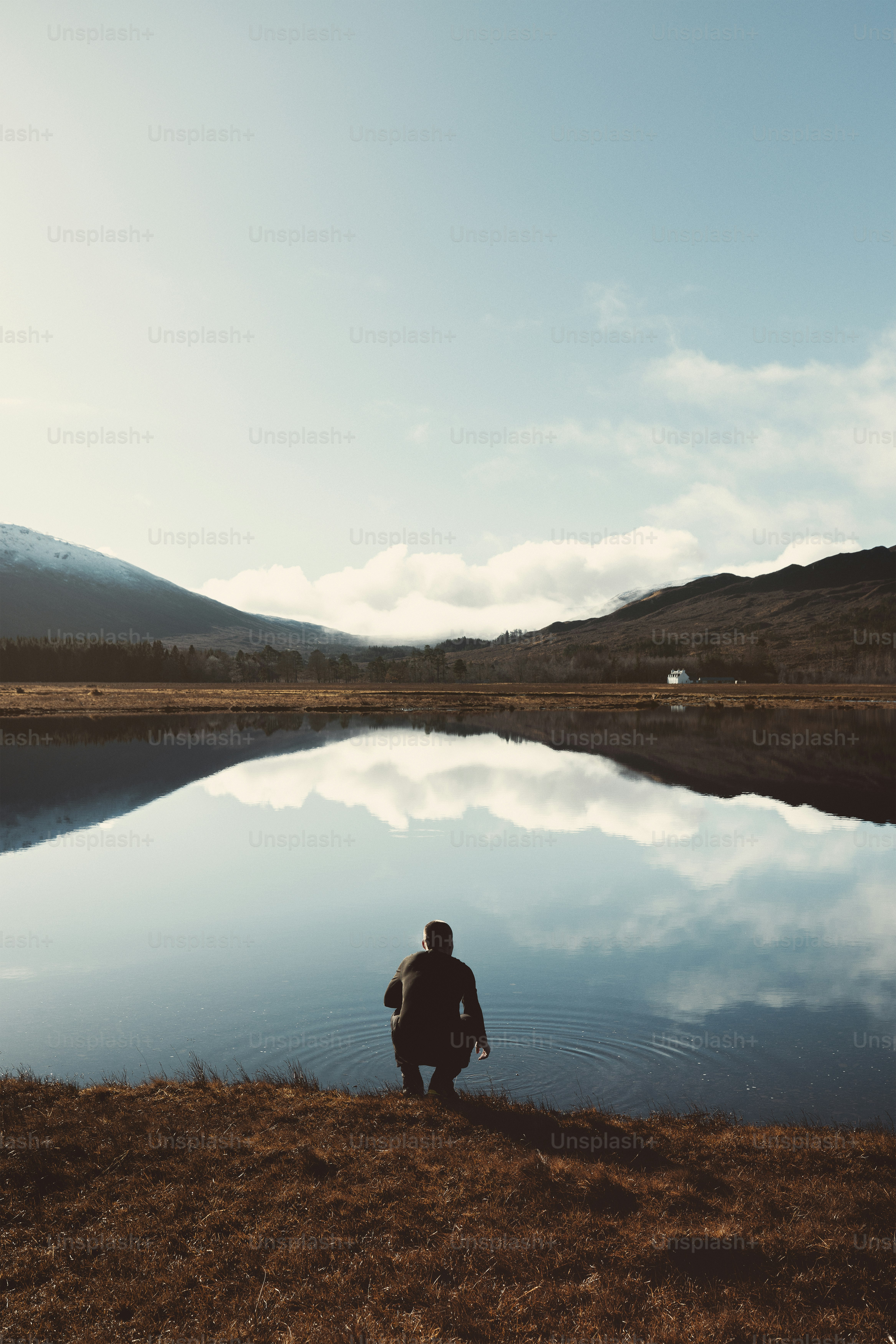 una persona seduta sulla riva di un lago