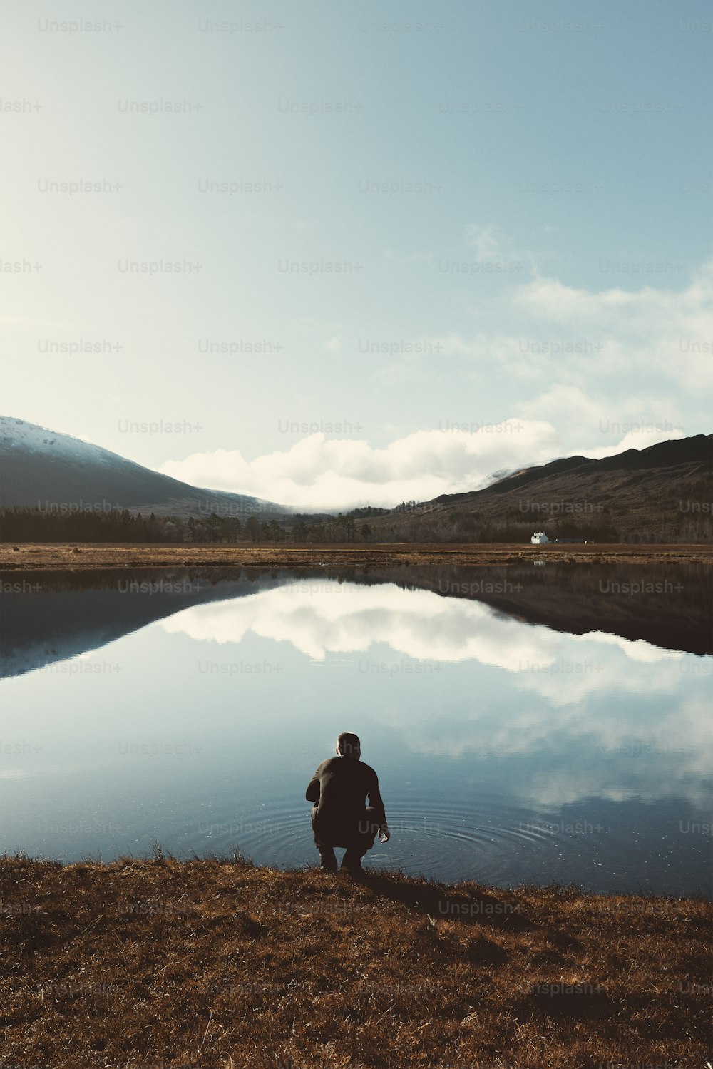 una persona sentada en la orilla de un lago