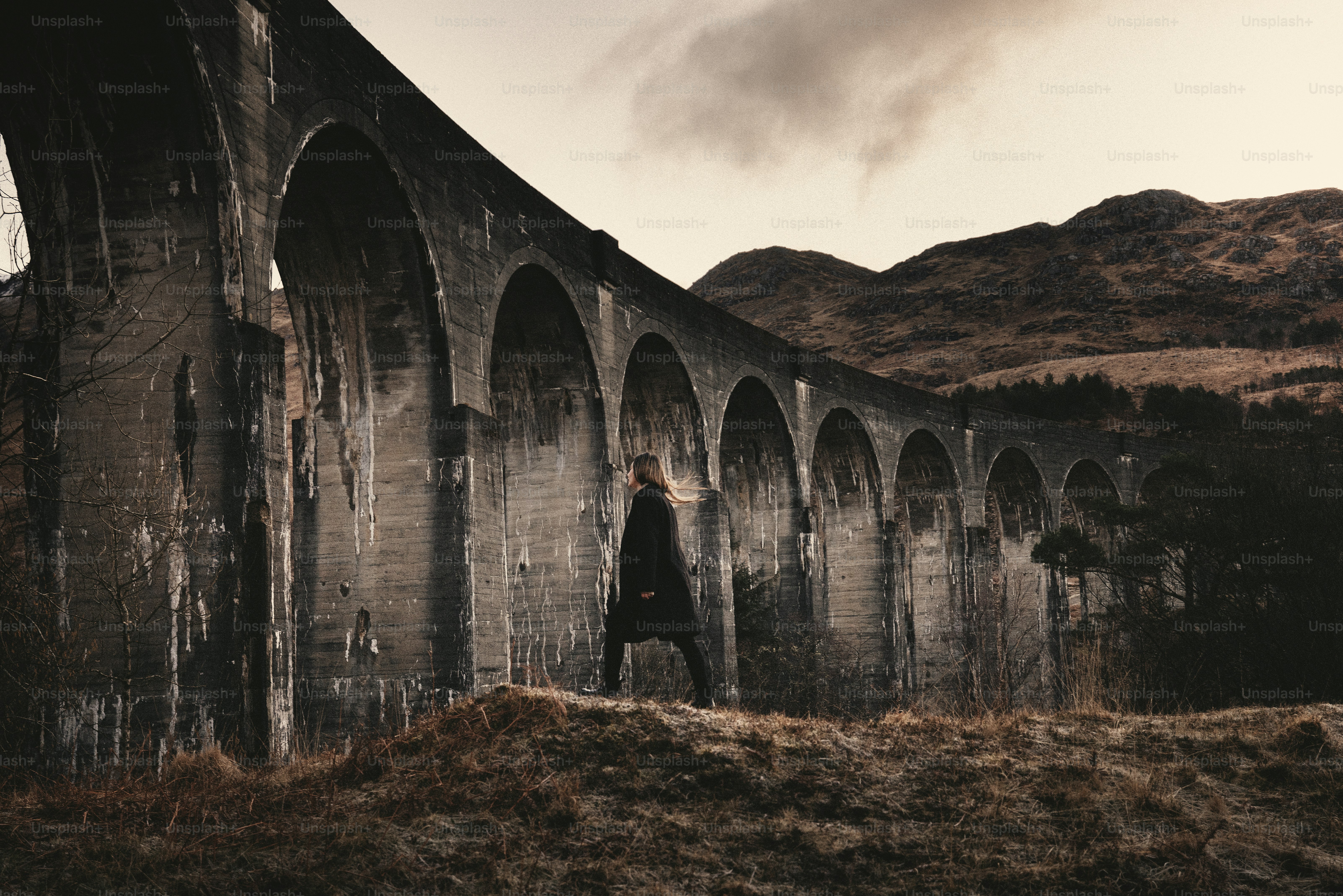 a person standing in front of an old bridge