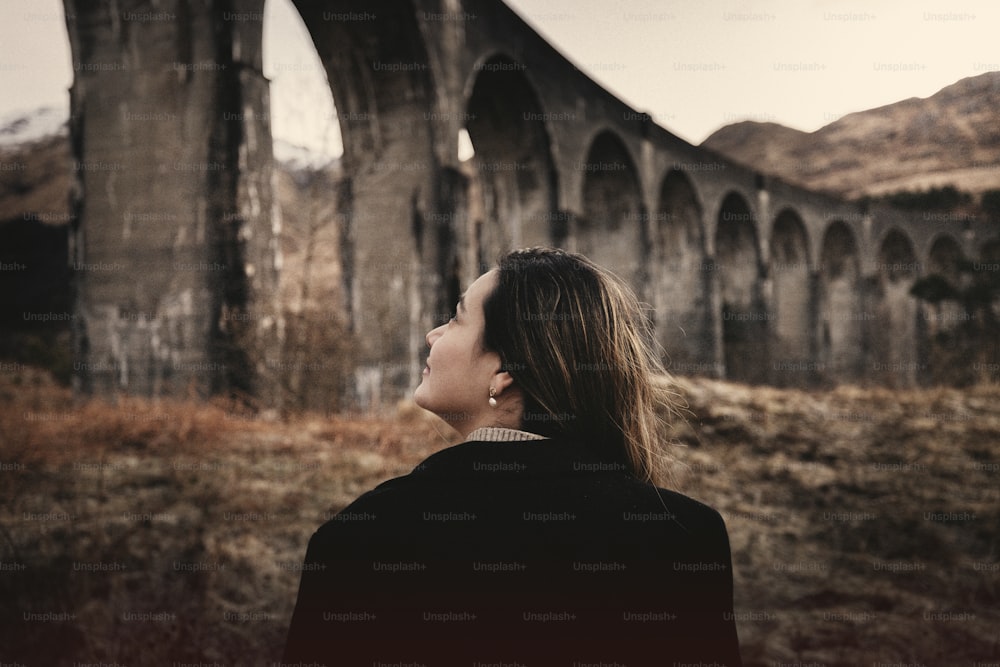 eine Frau steht vor einer alten Brücke