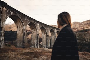 a woman standing in front of an old bridge