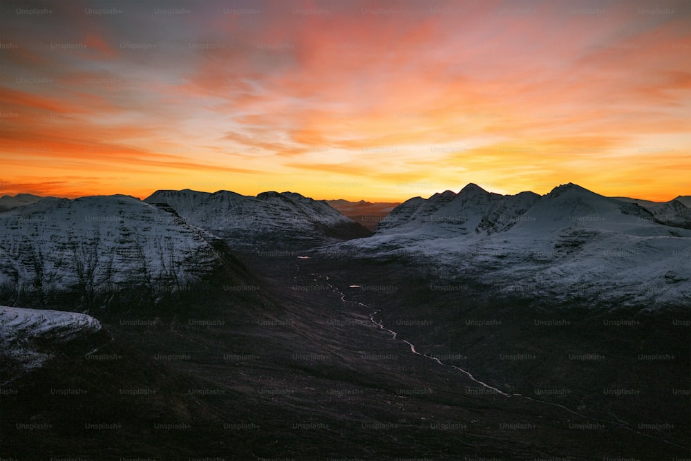 Una vista de una cadena montañosa con una puesta de sol al fondo