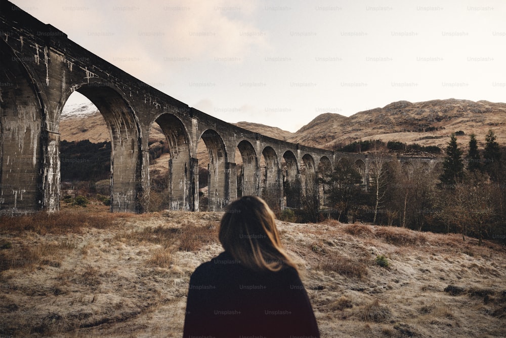 Une femme debout devant un vieux pont