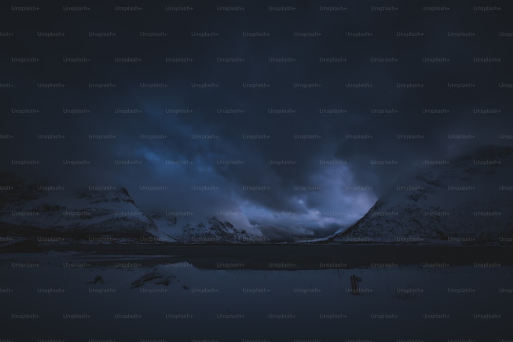 a dark sky with clouds over a mountain range