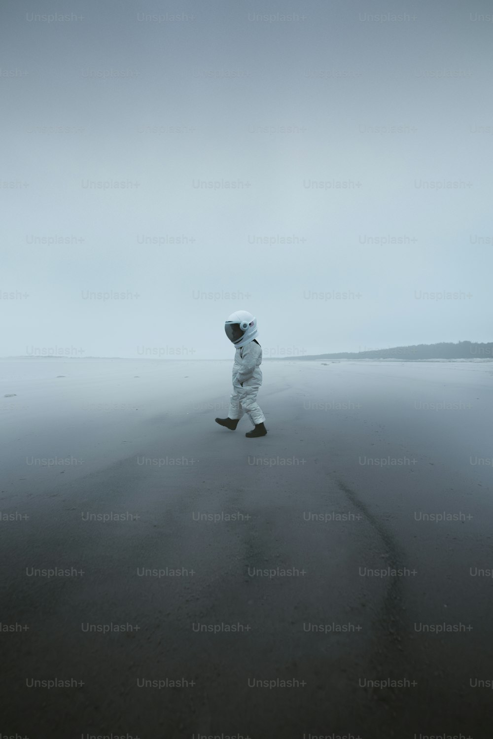 a person in a white suit walking on a beach