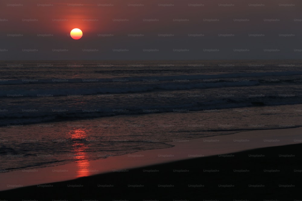 Il sole sta tramontando sull'oceano sulla spiaggia
