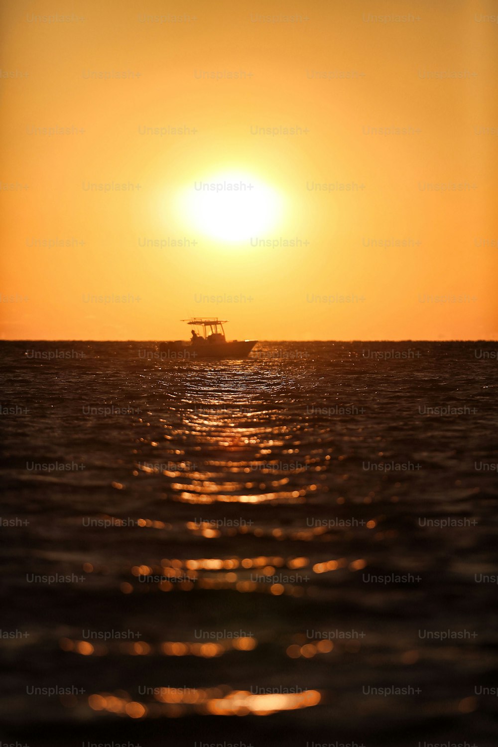 Ein Boot im Meer bei Sonnenuntergang mit der Sonne im Hintergrund
