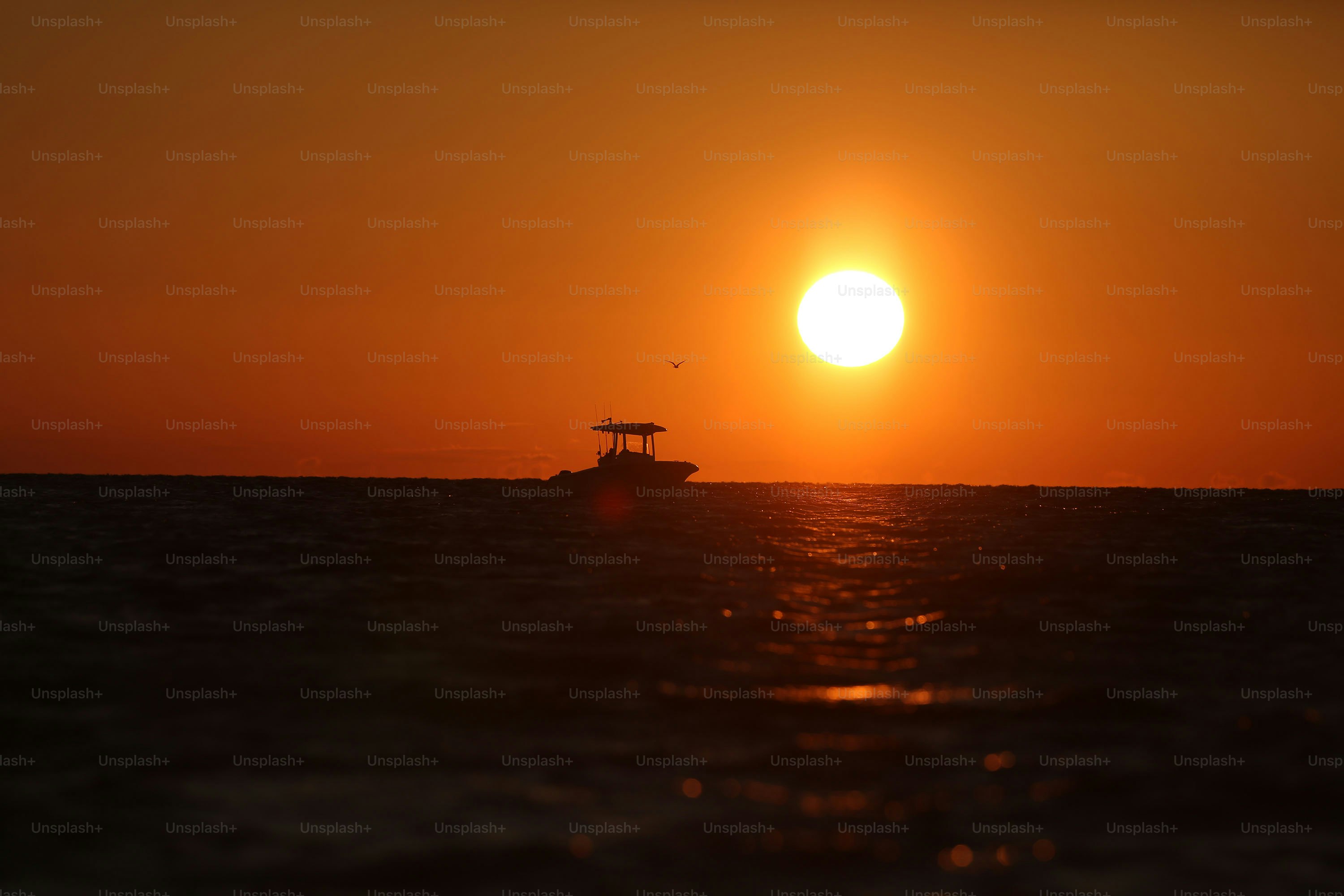 um pequeno barco no meio do oceano ao pôr do sol