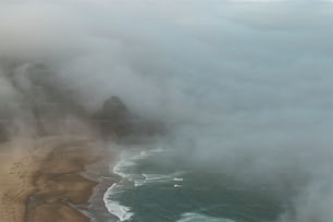 uma vista aérea de uma praia e oceano coberto de nuvens