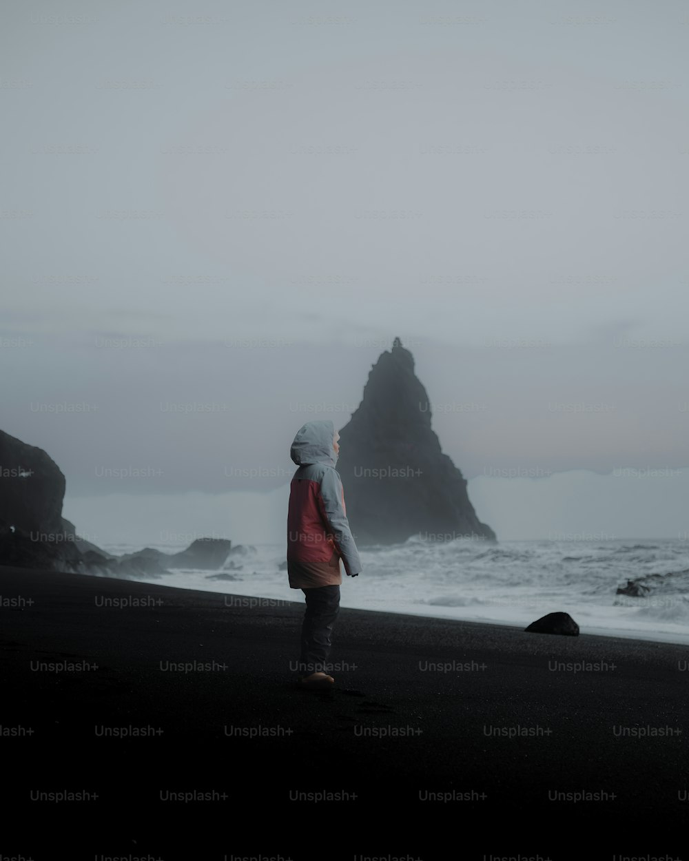 une personne debout sur une plage à côté de l’océan