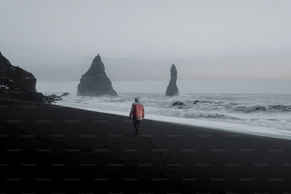 una persona che cammina su una spiaggia vicino all'oceano