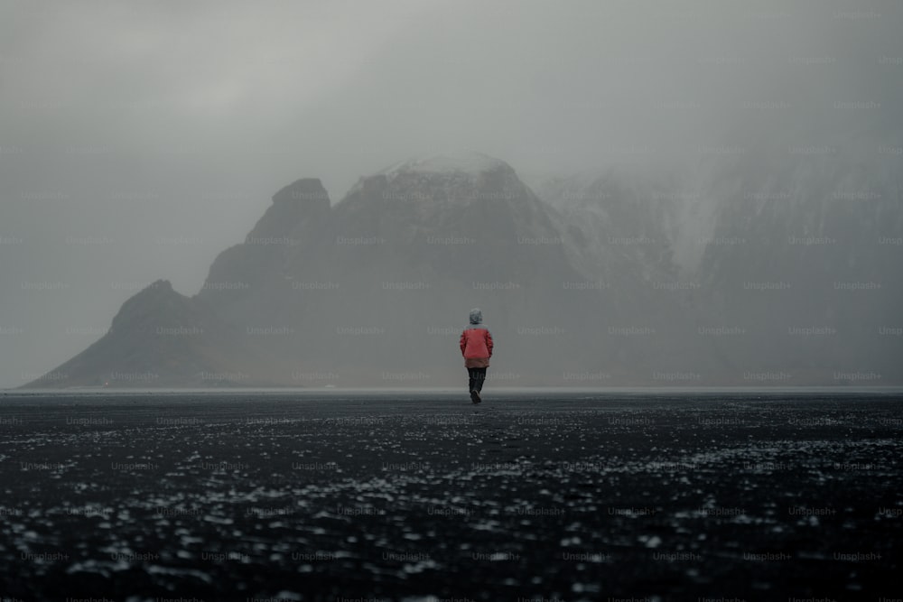 una persona in una giacca rossa che cammina su una spiaggia