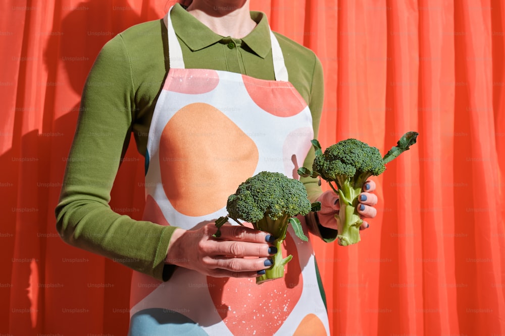 uma mulher em um avental segurando um pedaço de brócolis