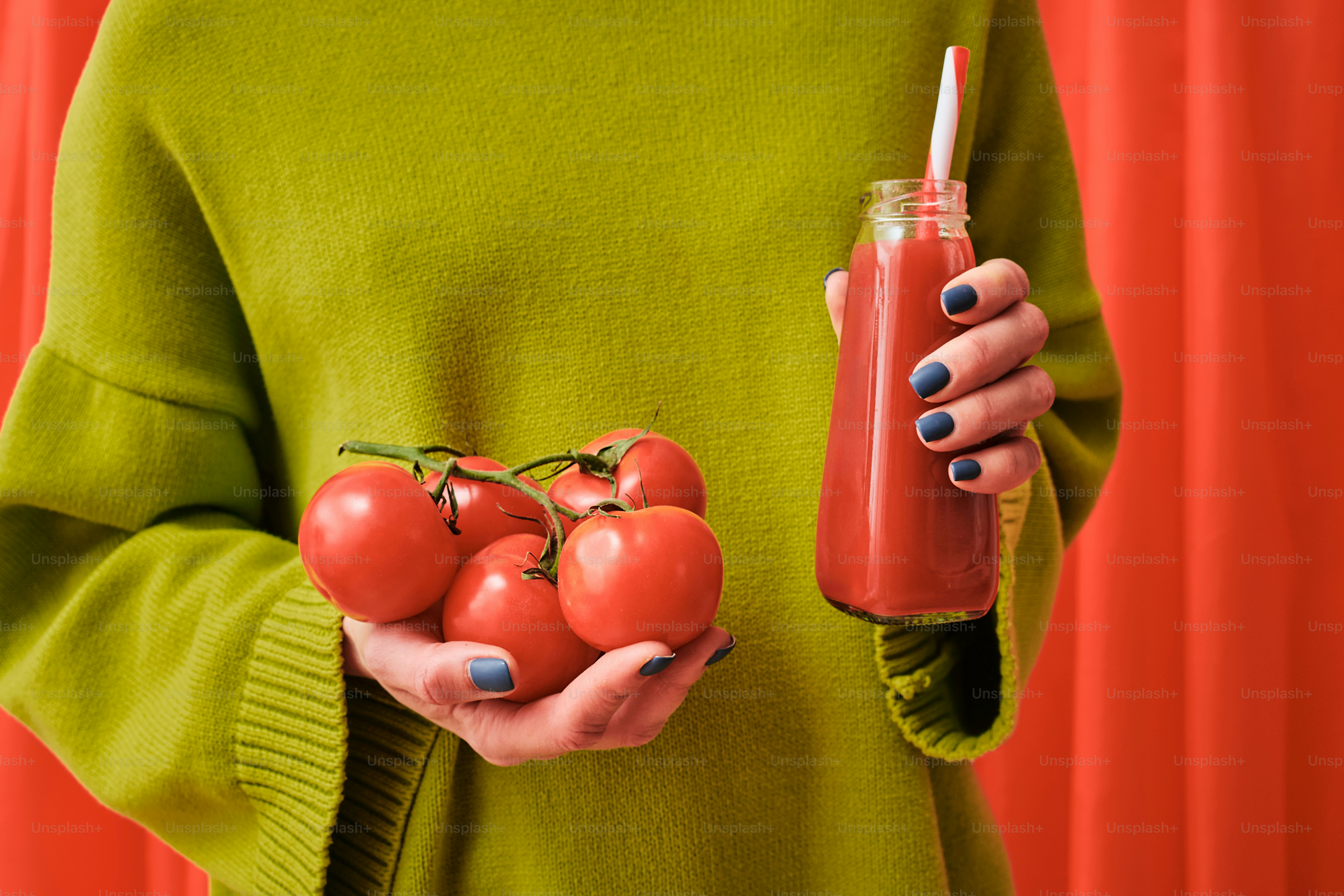 a woman in a green sweater holding tomatoes and a drink