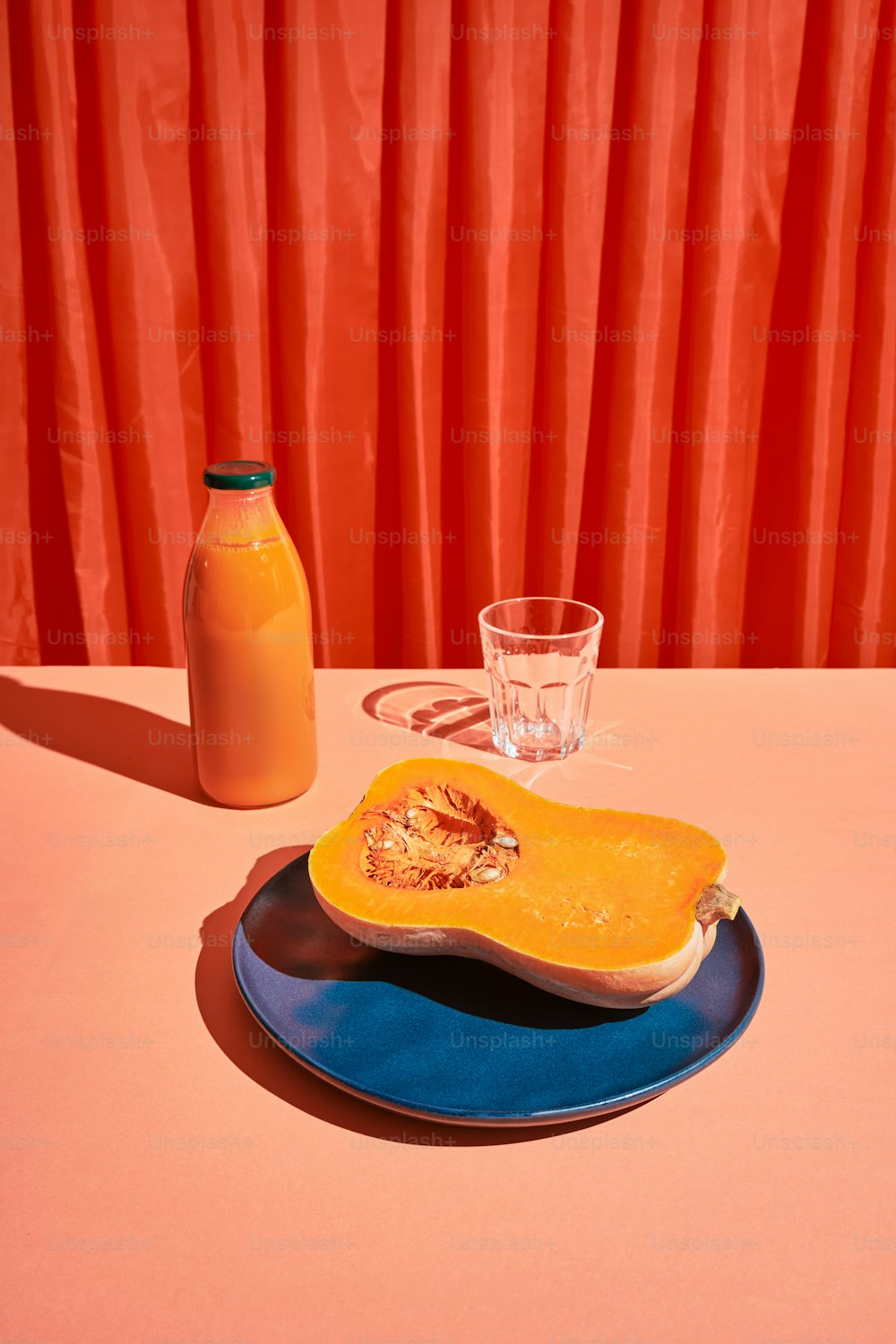 un vaso de jugo de naranja junto a una calabaza con mantequilla
