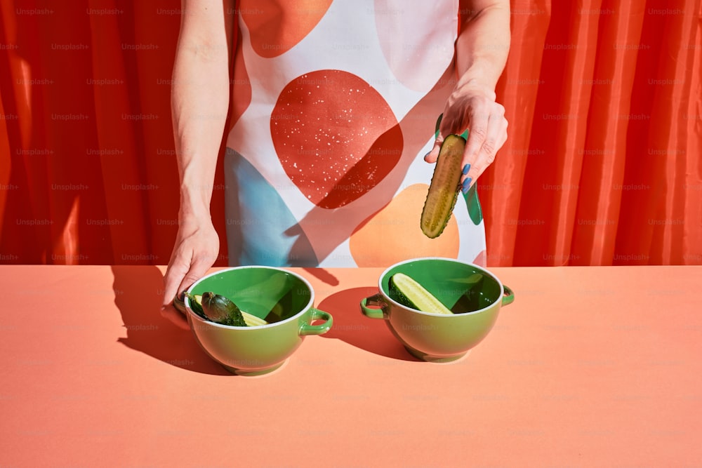 a woman holding a pickle over two green bowls