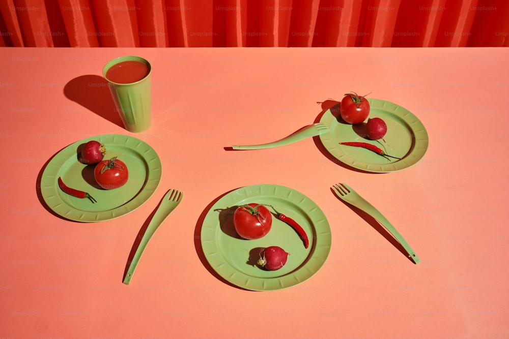 una mesa rosa con un plato verde y una taza verde