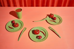 uma mesa rosa com um prato verde e um copo verde