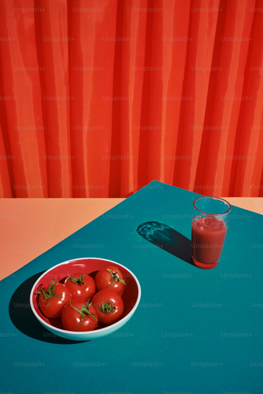 a bowl of tomatoes next to a glass of juice