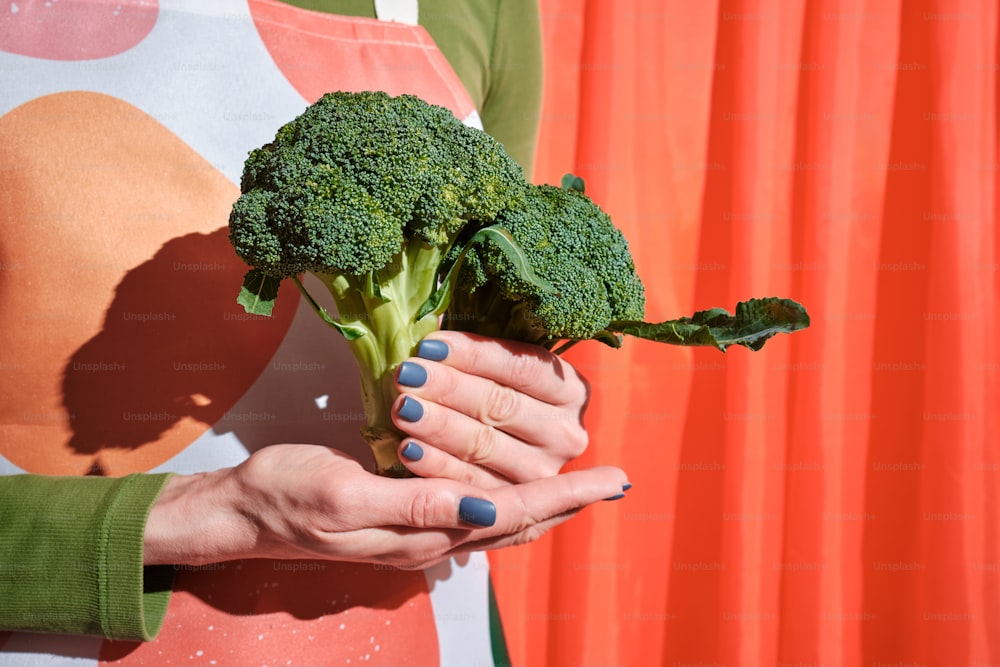 a woman holding a piece of broccoli in her hands