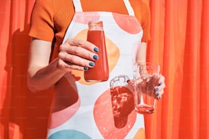 a woman holding a glass and a bottle of juice