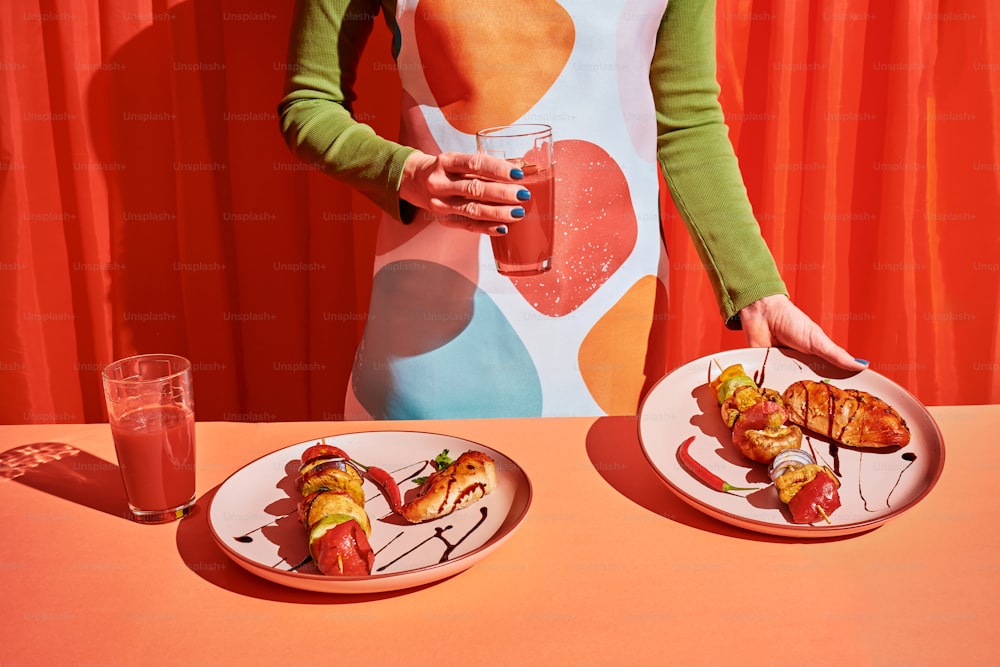 una mujer de pie junto a una mesa con dos platos de comida