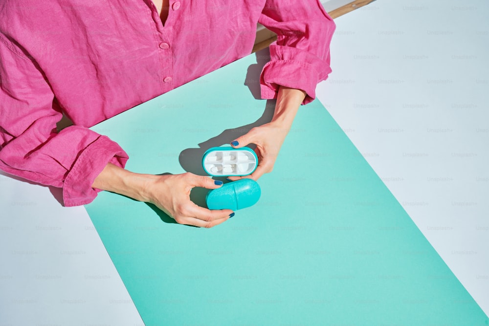 a woman in a pink shirt is holding a blue object