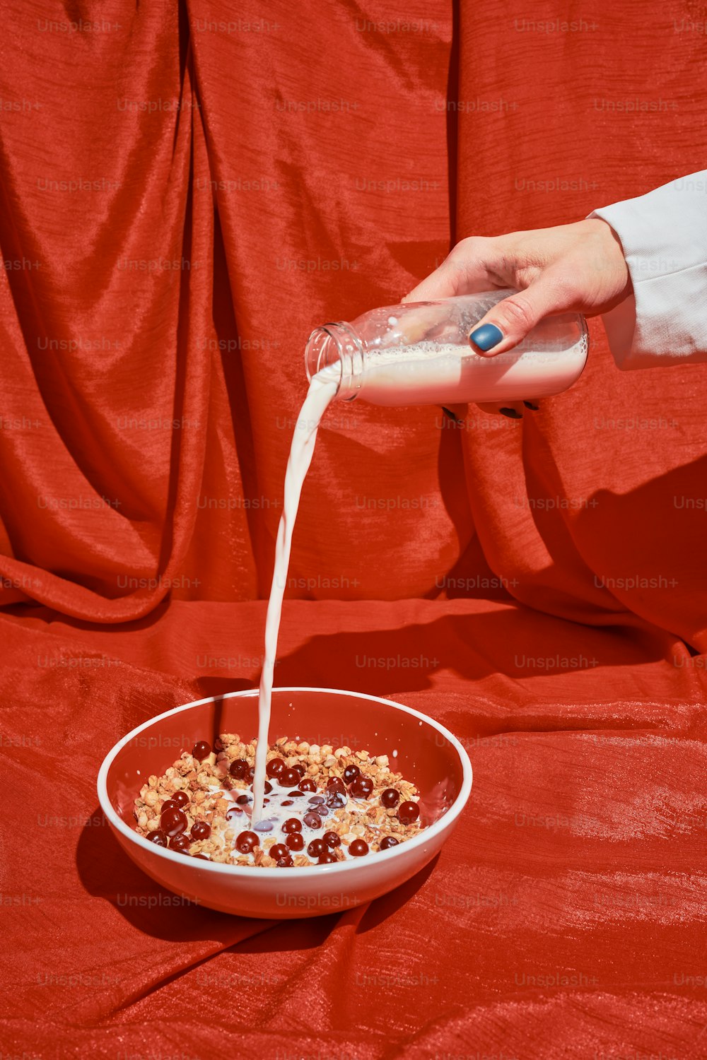 une personne versant du lait dans un bol de céréales ;
