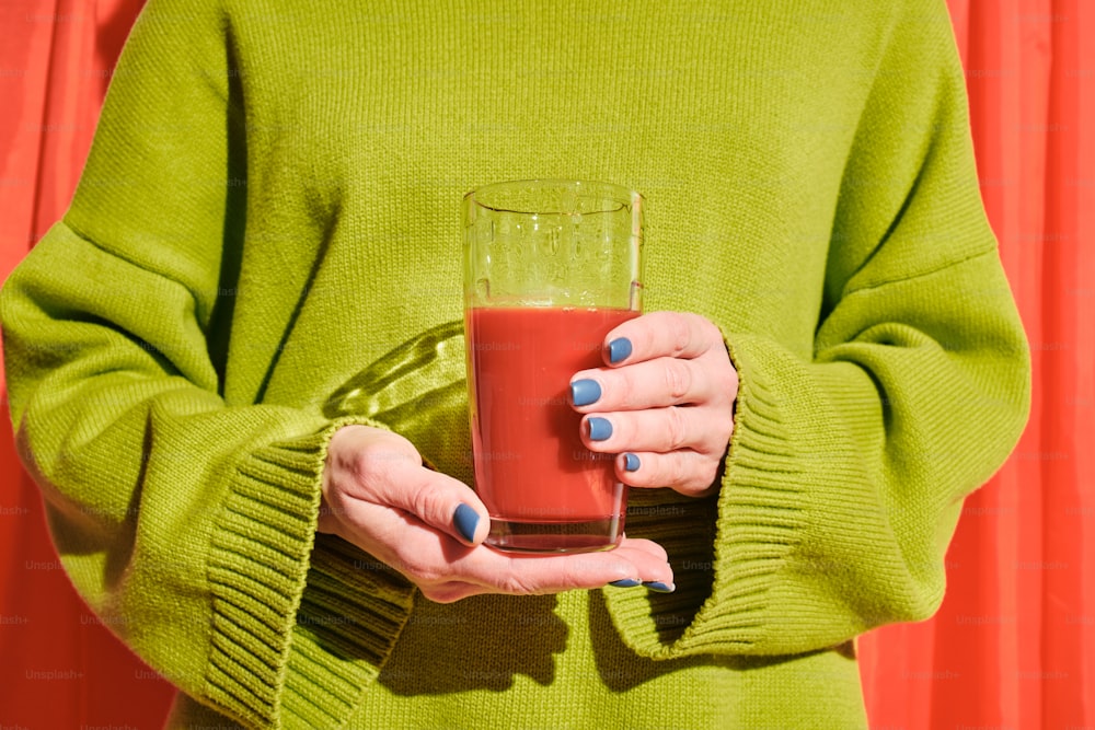 a woman holding a glass of red liquid