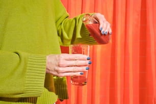 a woman in a green sweater holding a glass of liquid