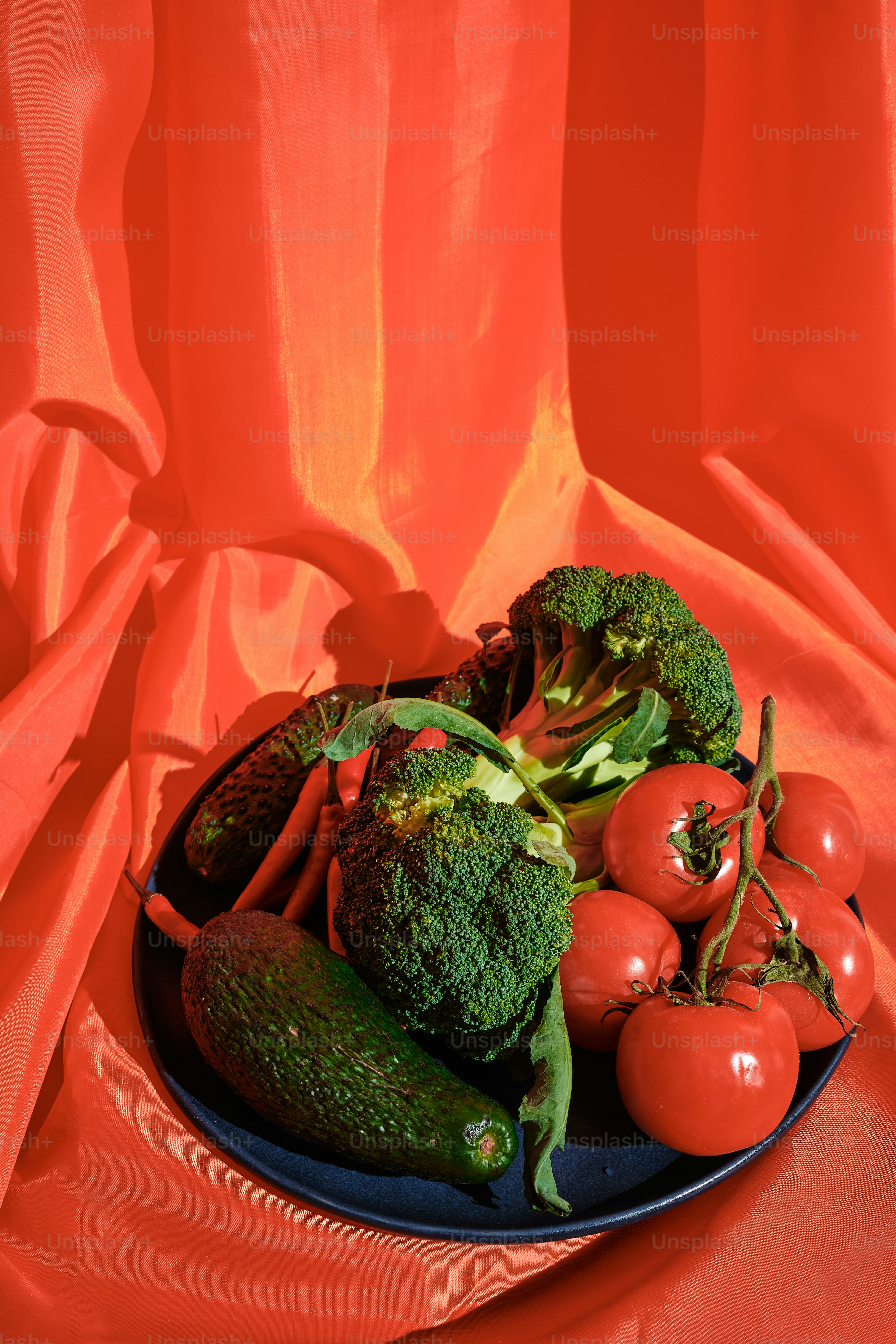 a plate of broccoli, tomatoes, cucumbers and broccoli