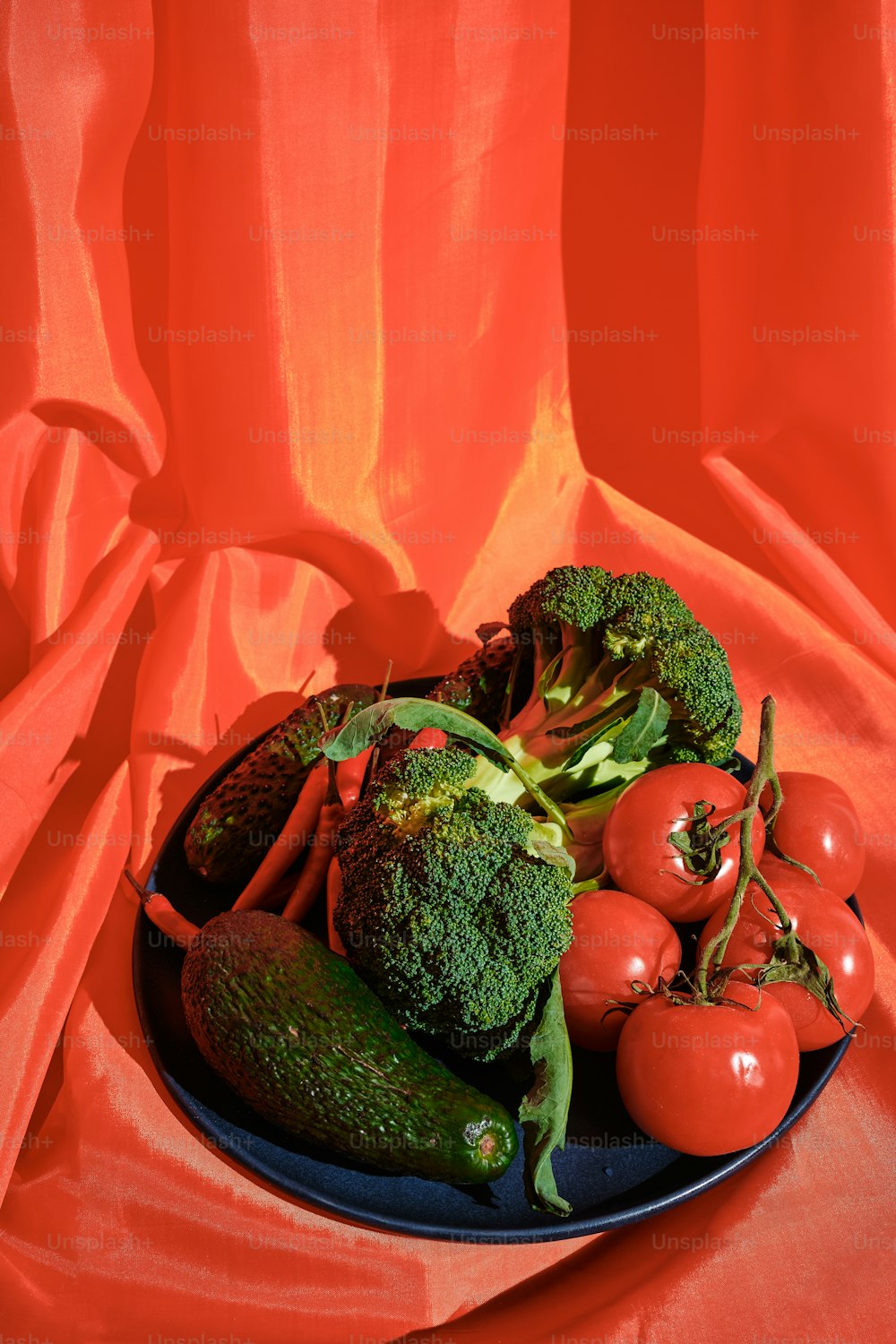 a plate of broccoli, tomatoes, cucumbers and broccoli