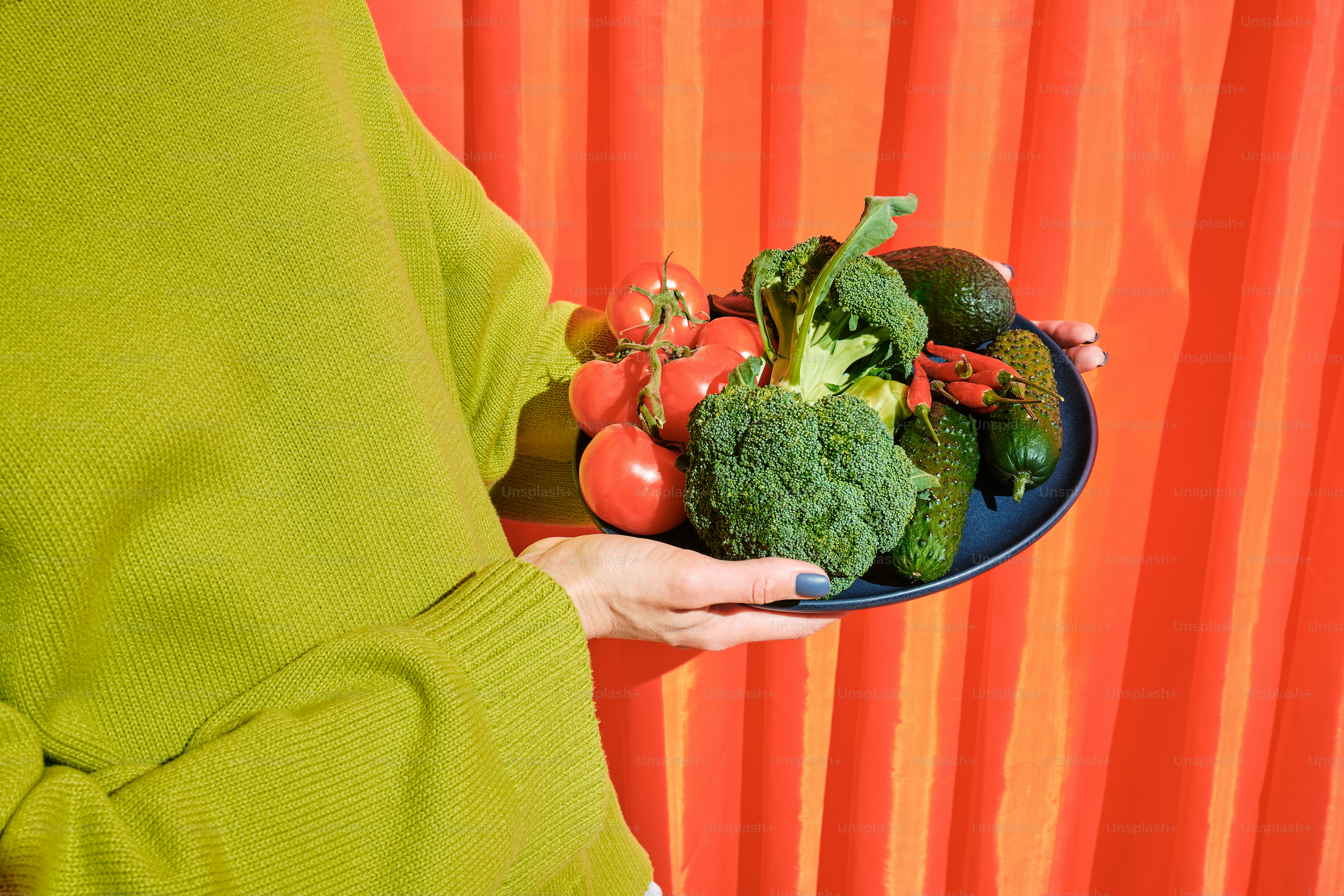 a woman holding a plate of fresh vegetables
