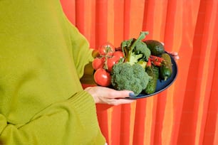 a woman holding a plate of fresh vegetables