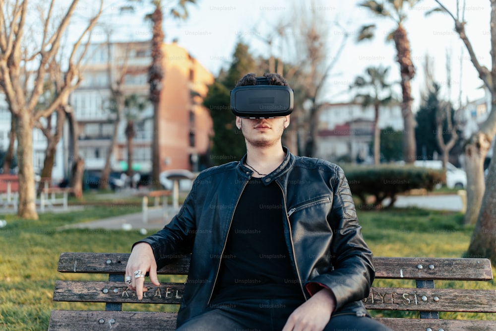 a man sitting on a park bench wearing a virtual headset