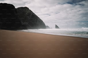 una playa de arena con una formación rocosa al fondo