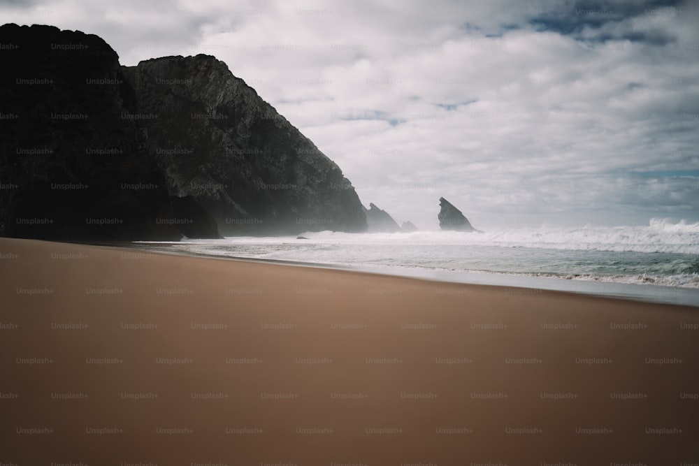 uma praia de areia com uma formação rochosa ao fundo