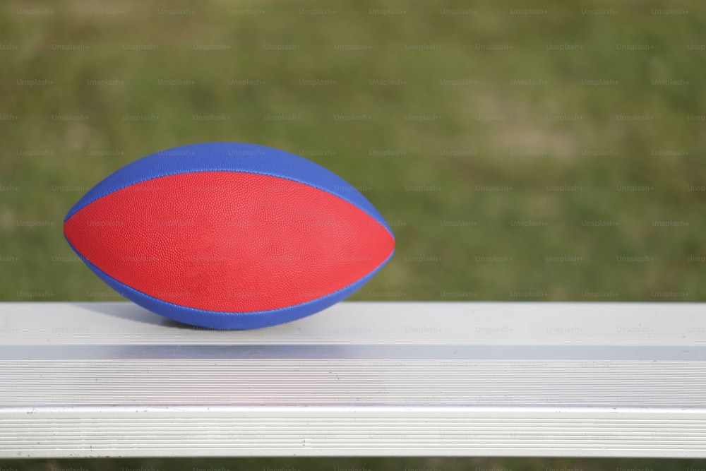 a red and blue ball sitting on top of a white bench