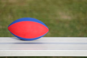 a red and blue ball sitting on top of a white bench