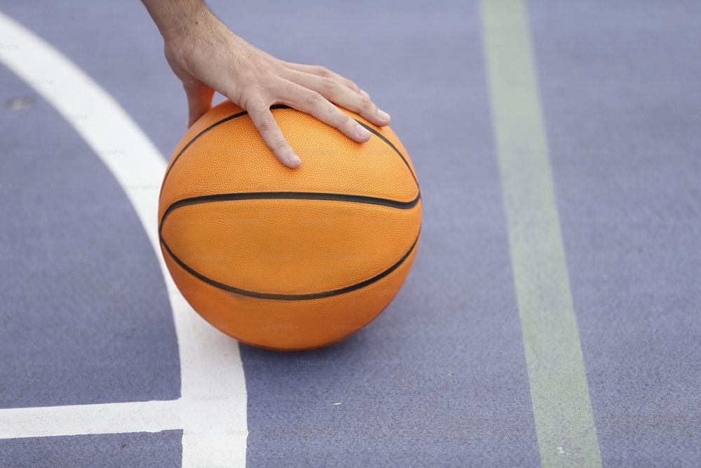 uma pessoa segurando uma bola de basquete em uma quadra de basquete