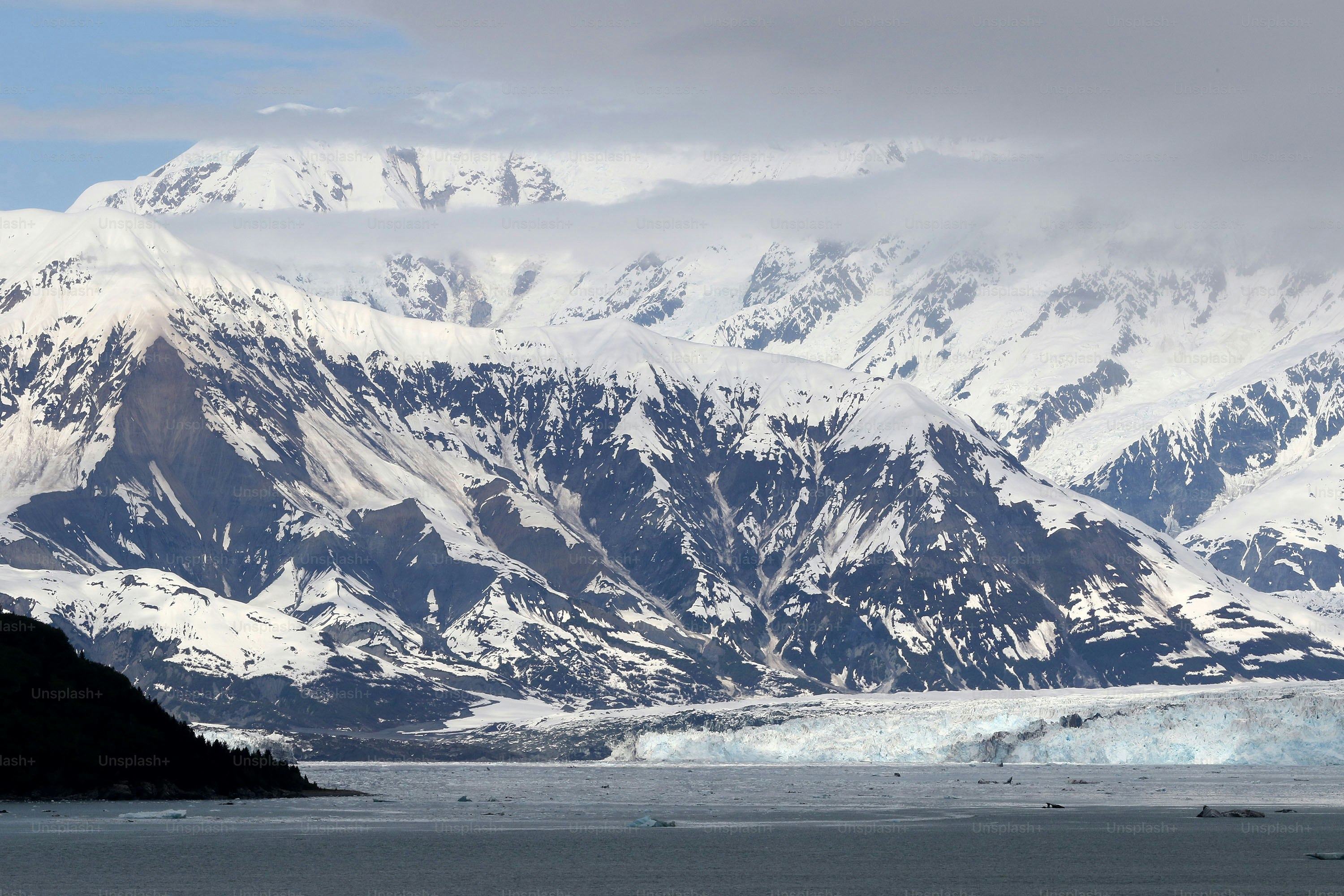 une grande montagne recouverte de neige à côté d’un plan d’eau