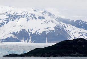 a large mountain covered in snow next to a body of water