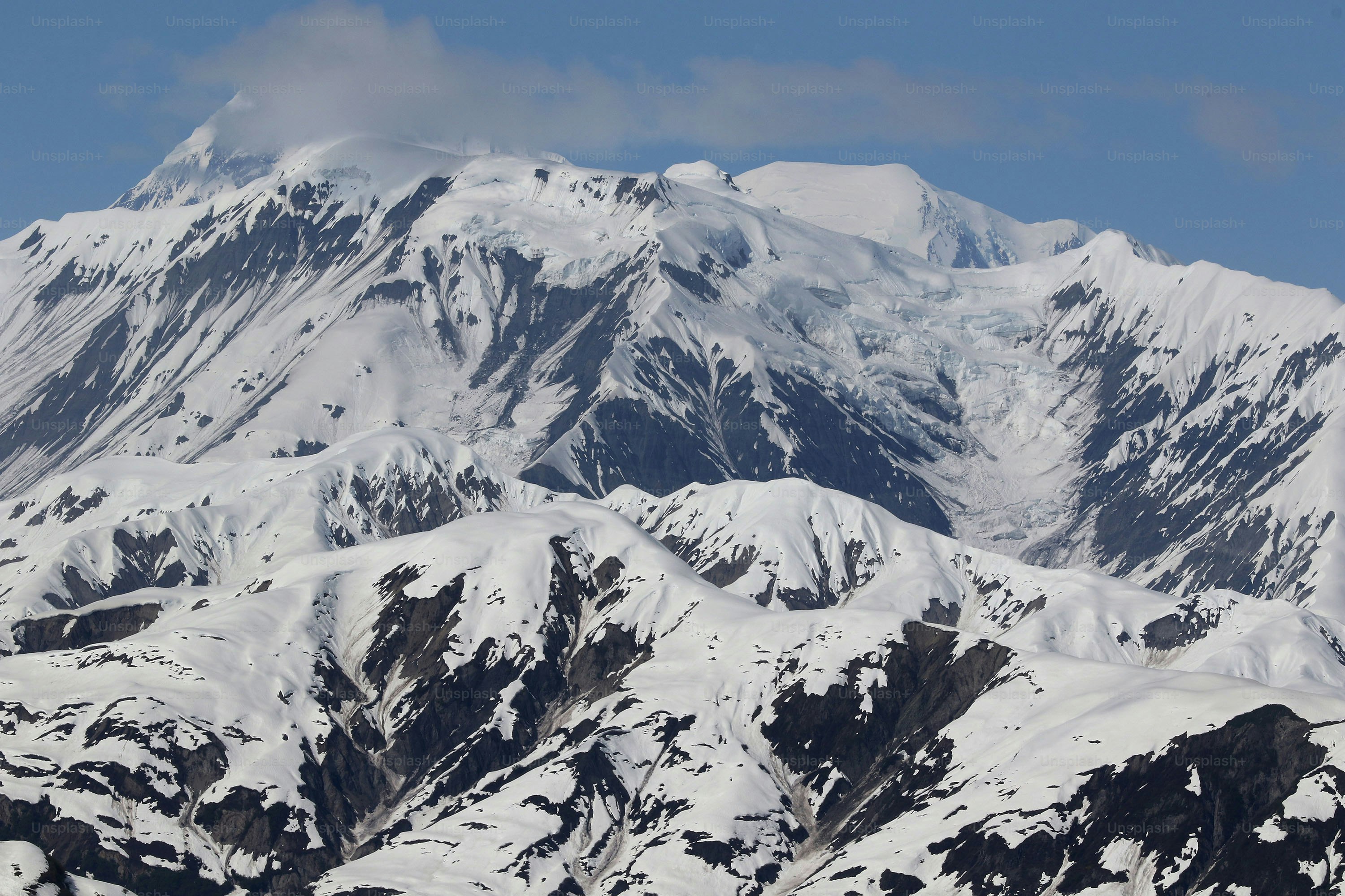 a large mountain covered in snow under a blue sky