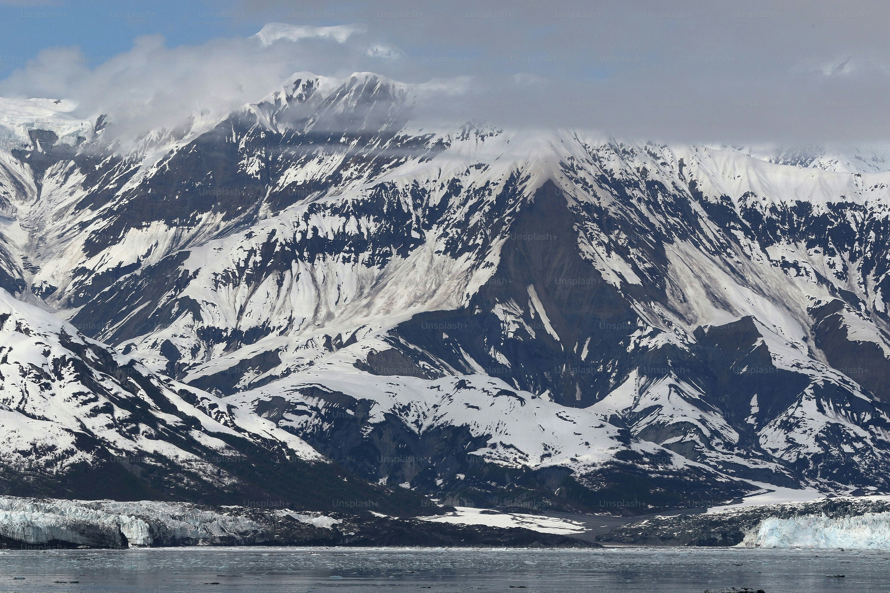 une grande montagne recouverte de neige à côté d’un plan d’eau
