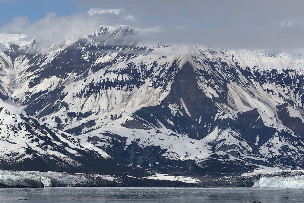 une grande montagne recouverte de neige à côté d’un plan d’eau