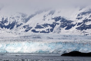 Un gran glaciar con montañas cubiertas de nieve al fondo