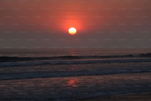 the sun is setting over the ocean on a cloudy day